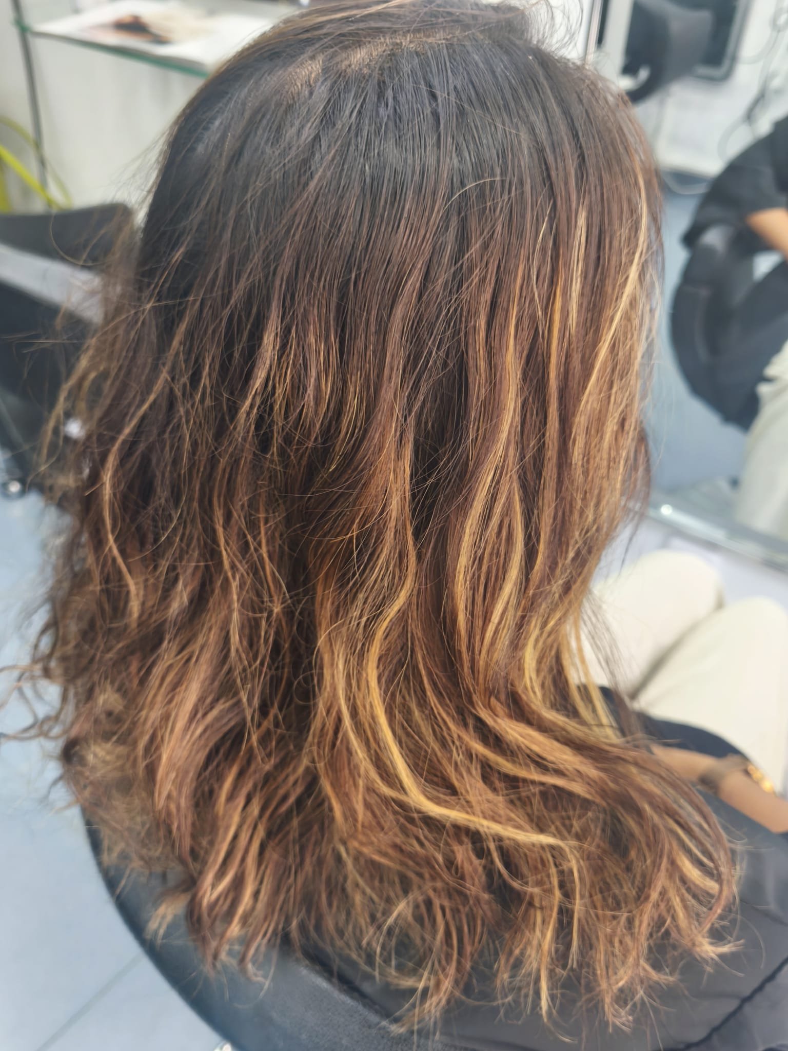 Antes de las mechas: cabello castaño ondulado con raíces oscuras y mechas crecidas