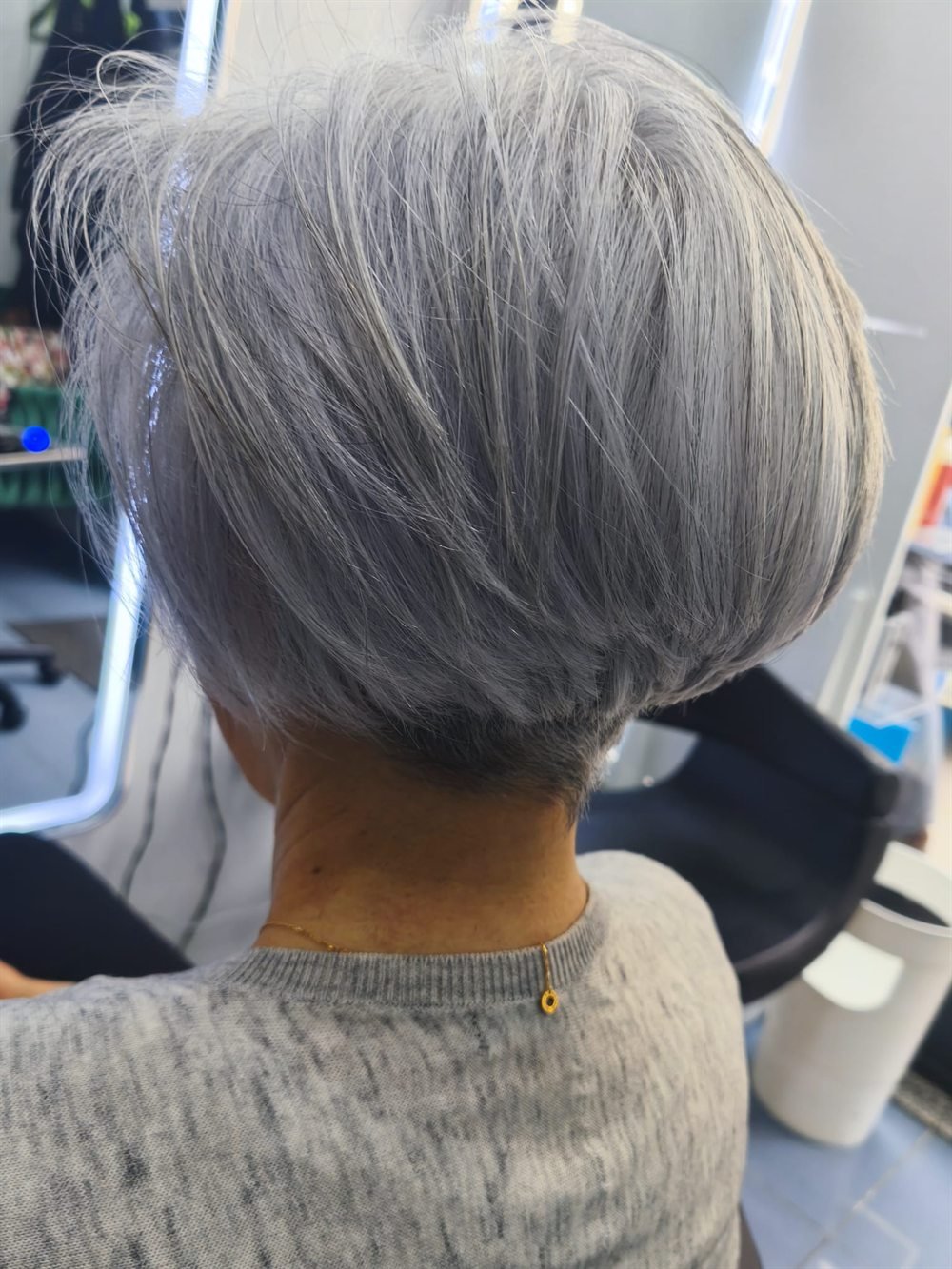 Corte bob corto sobre cabello plateado natural, con la nuca perfilada