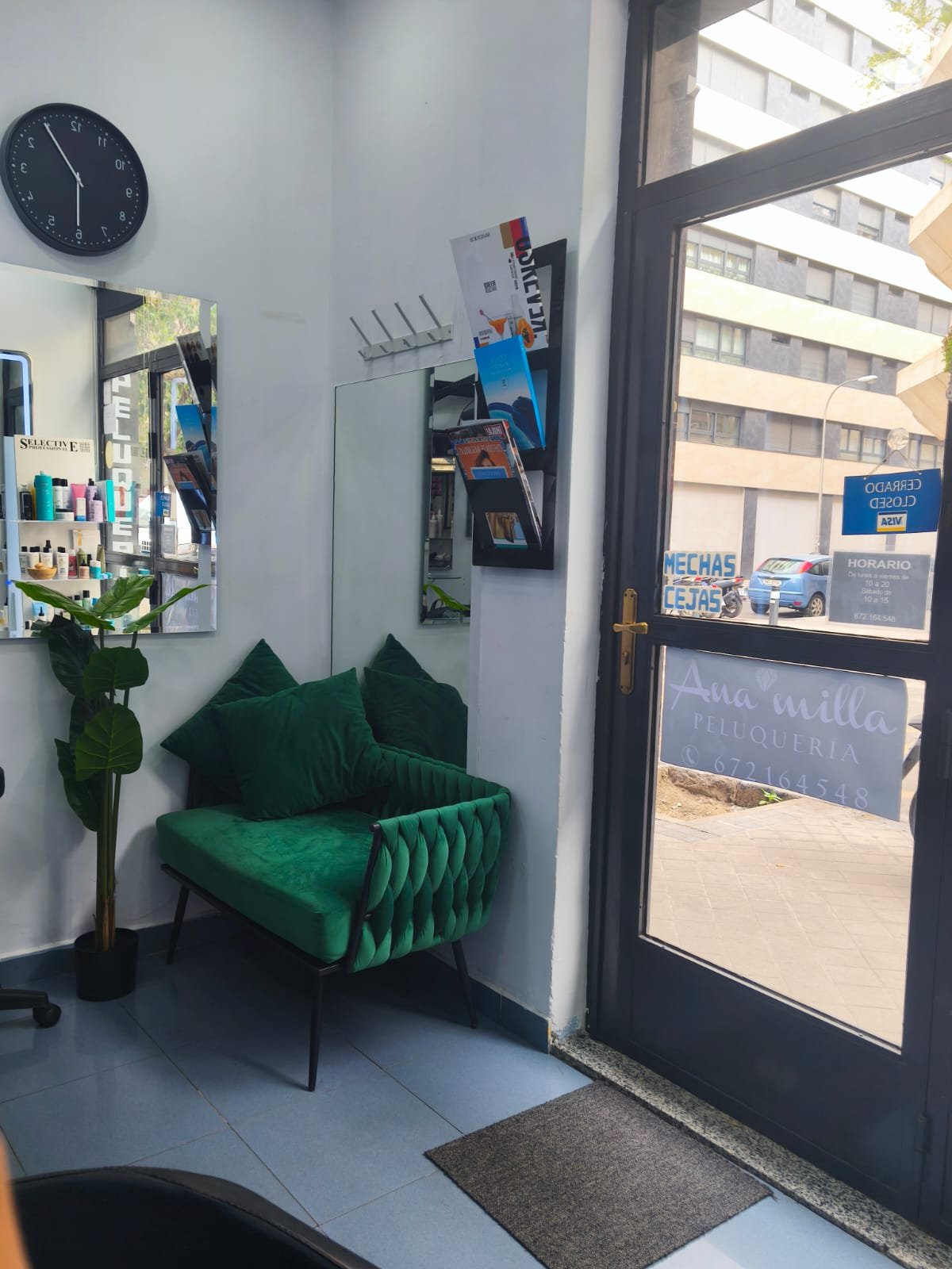 Rincón de espera del salón, con sofá de terciopelo verde junto a la entrada