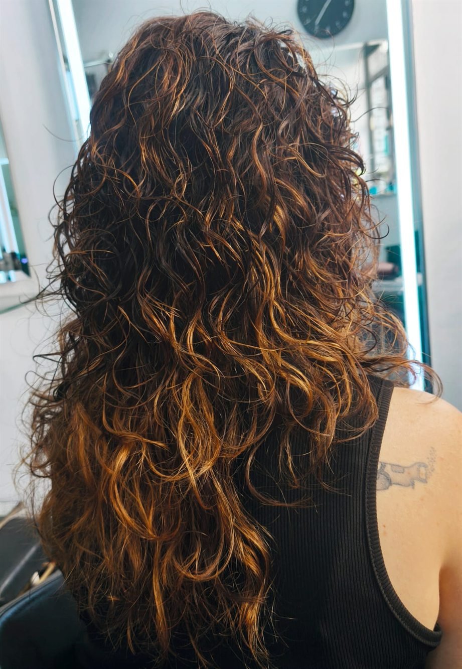 Mechas cobrizas sobre melena larga rizada, con el rizo definido
